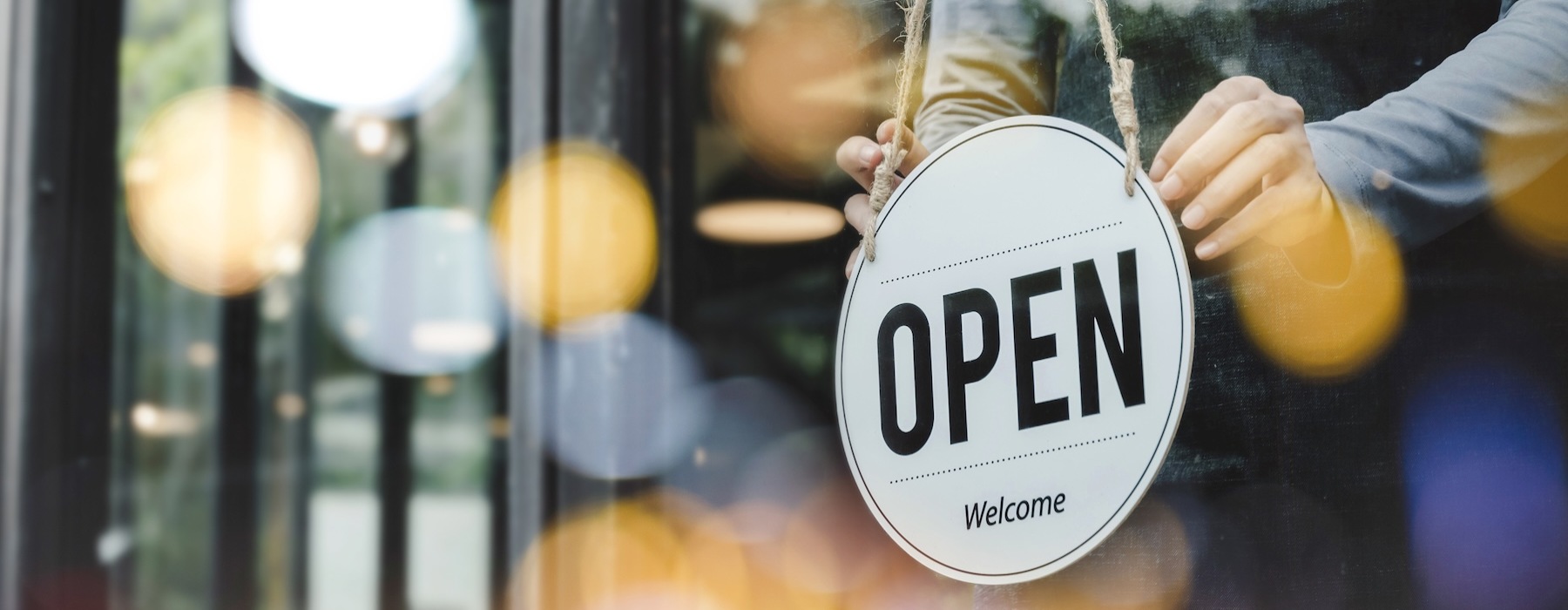 a person turning an open sign starting the day