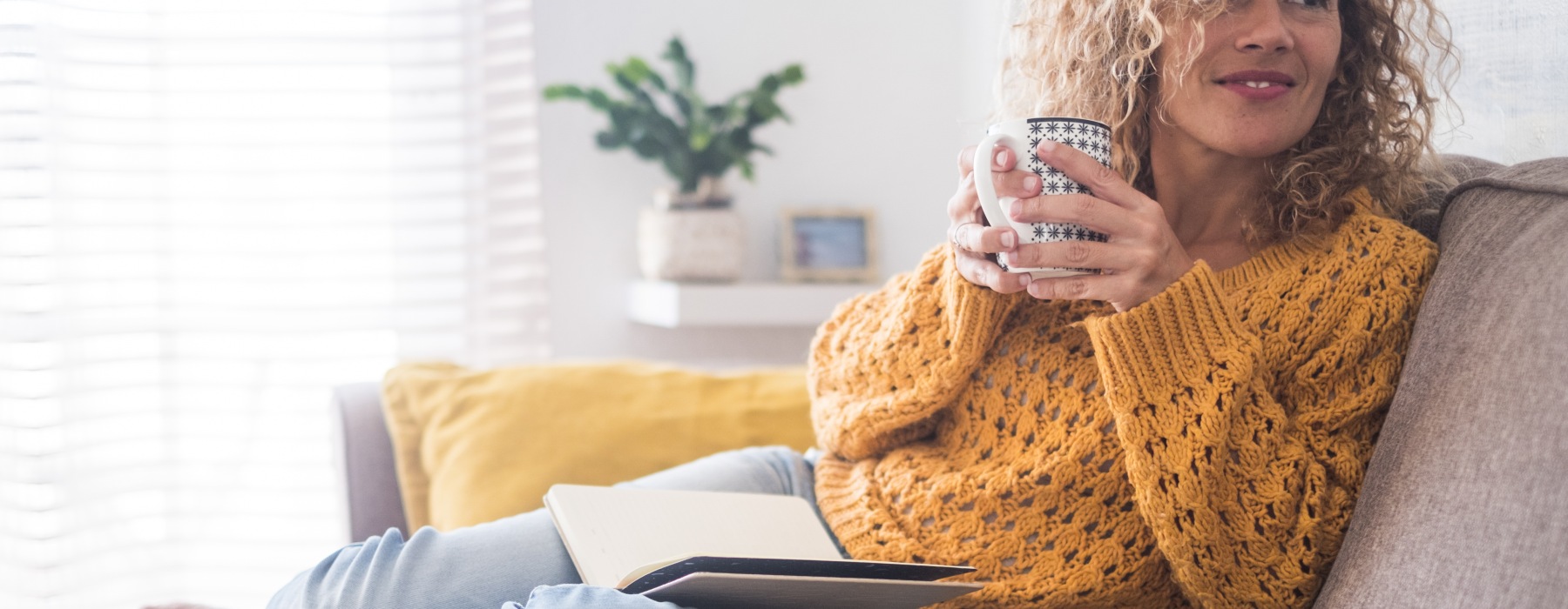 woman on couch with book and coffee cup