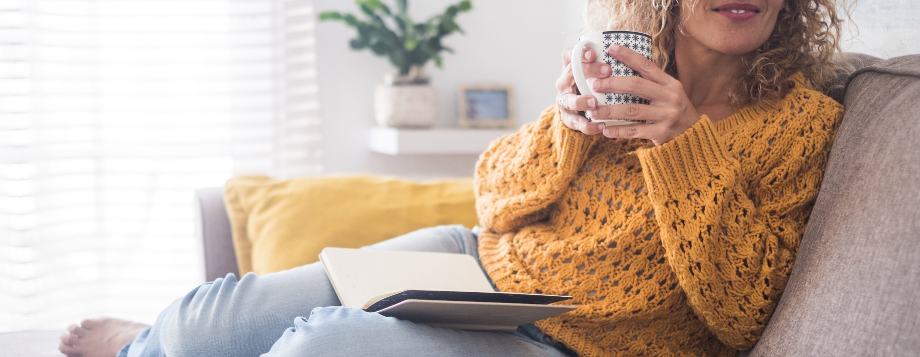 woman on couch with book and coffee cup